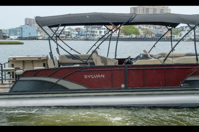 Slide: The Image of 2023 Sylvan L5 DLZ Bar pontoon boat on a scenic waterfront. - 1