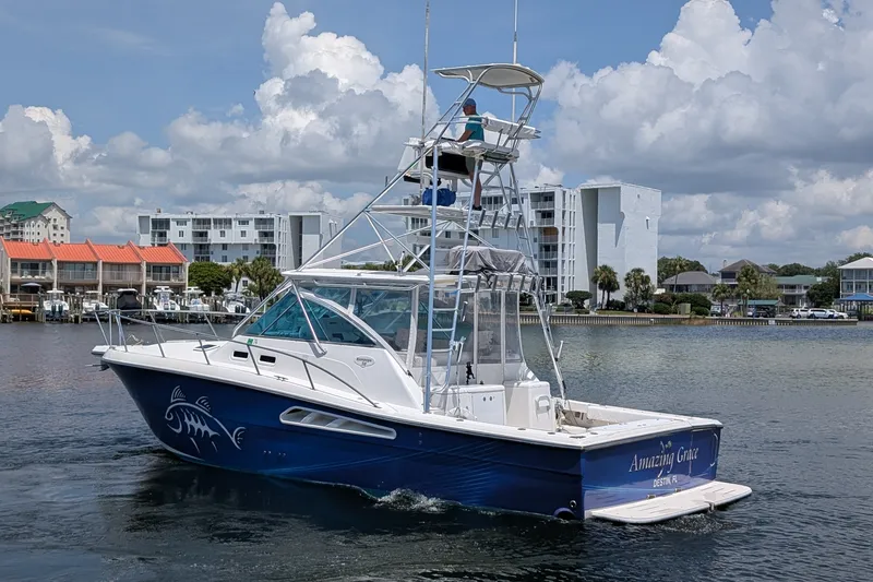 Slide: The Image of 2005 Rampage 38 Express boat cruising near coastal buildings under a cloudy sky. - 1