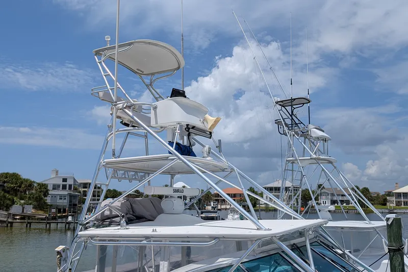 Slide: The Image of 2005 Rampage 38 Express boat with tower, docked near waterfront homes under a blue sky. - 3