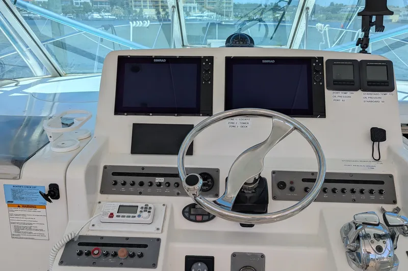 Slide: The Image of Control panel of a 2005 Rampage 38 Express boat with steering wheel and navigation screens. - 16