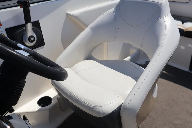 Slide: The Image of Captain's seat in 2012 Larson LX 2150 boat, featuring white upholstery and steering controls. - 27