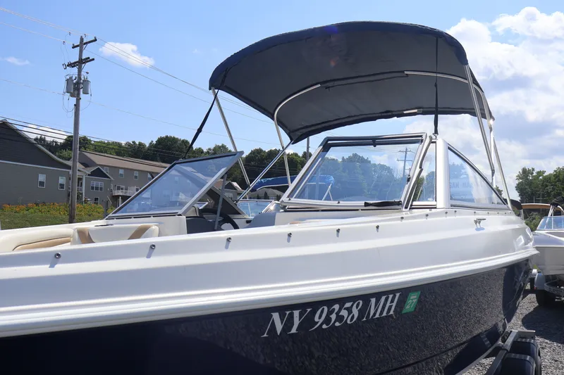 Slide: The Image of 2012 Larson LX 2150 boat with canopy, parked outdoors under a clear sky. - 5