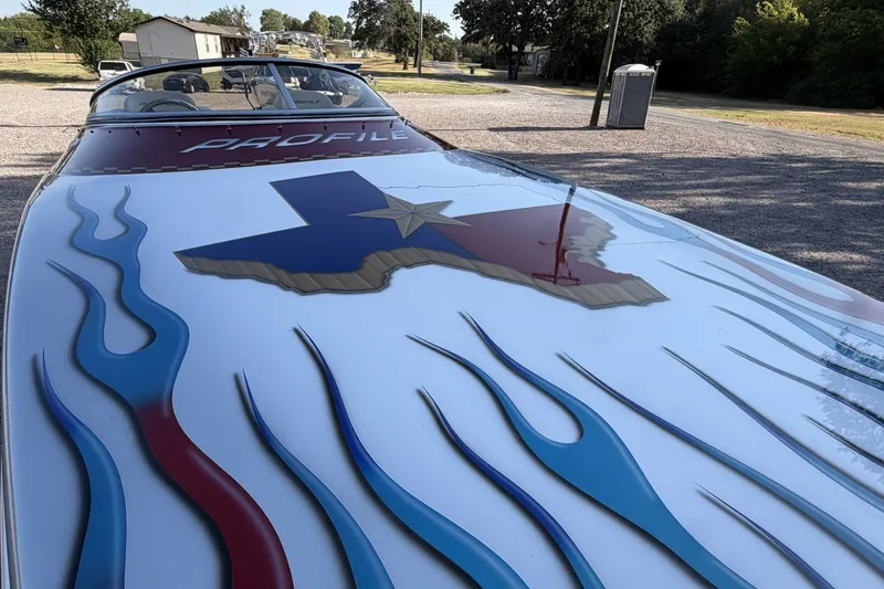 Slide: The Image of Profile 260 V boat with Texas-themed design and flame graphics, parked outdoors, 2006 model. - 27