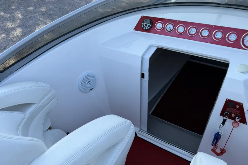 Slide: The Image of Interior of a 2006 Profile 260 V boat with white seating and red dashboard. - 17