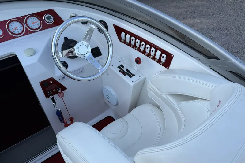 Slide: The Image of Steering console of a 2006 Profile 260 V boat with white seating and red accents. - 16