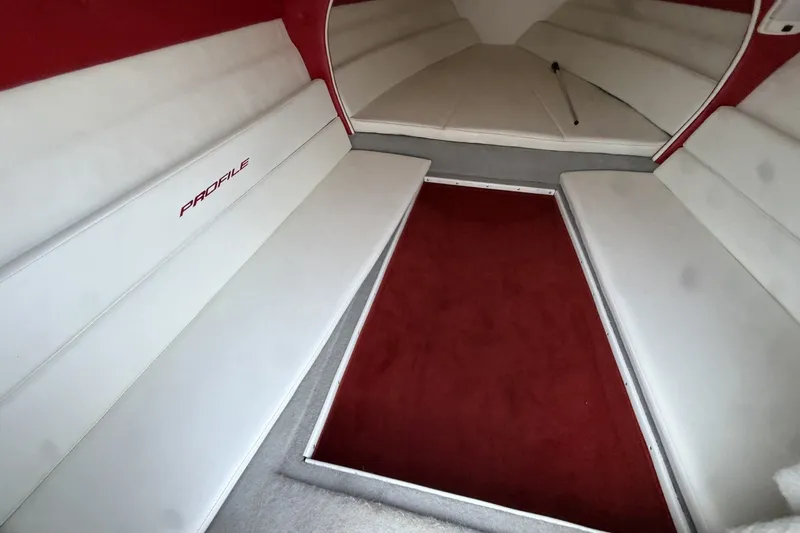 Slide: The Image of Interior of a 2006 Profile 260 V boat with white seating and red carpet. - 19
