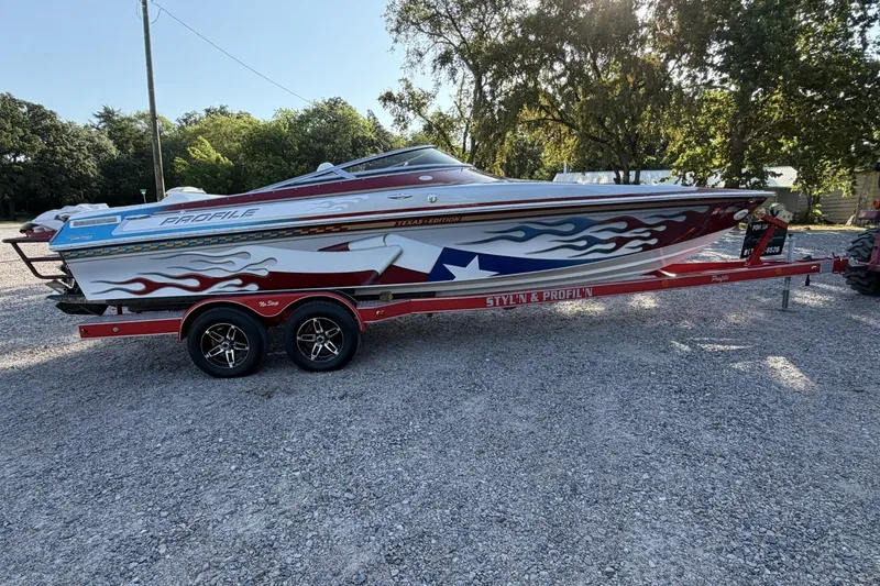 Slide: The Image of Sporty 2006 Profile 260 V boat with vibrant flame graphics on a red trailer. - 24