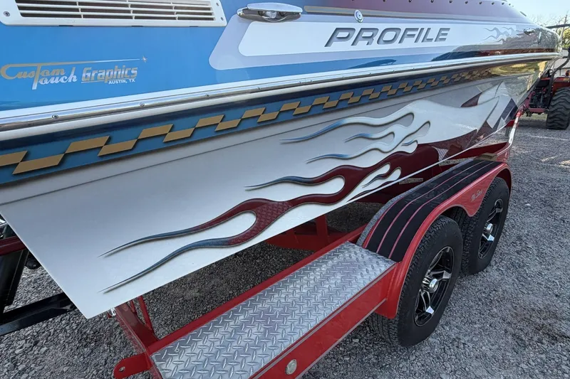 Slide: The Image of 2006 Profile 260 V boat with custom flame graphics on a red trailer. - 29