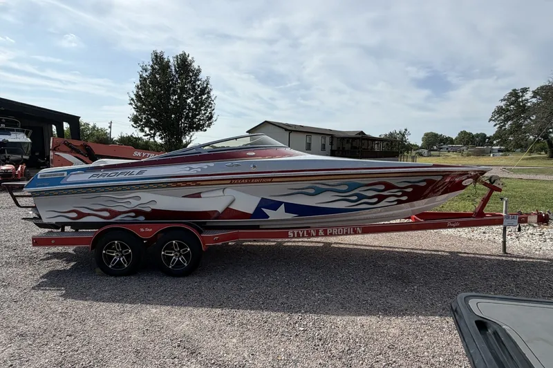 The Image of 2006 Profile 260 V boat with vibrant graphics on a red trailer, parked outdoors. - 1