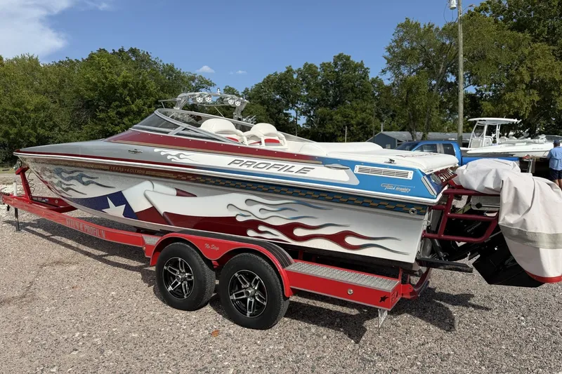 Slide: The Image of 2006 Profile 260 V speedboat with custom graphics on a red trailer, parked outdoors. - 4