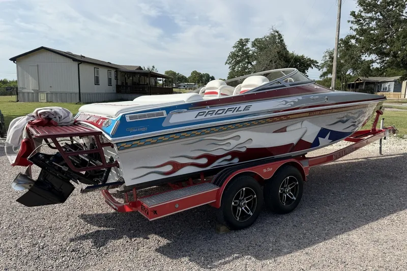 Slide: The Image of 2006 Profile 260 V speedboat with custom graphics on a red trailer, parked outdoors. - 2