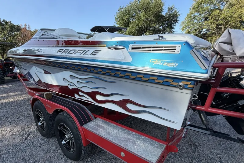 Slide: The Image of 2006 Profile 260 V speedboat with custom graphics on a red trailer. - 33