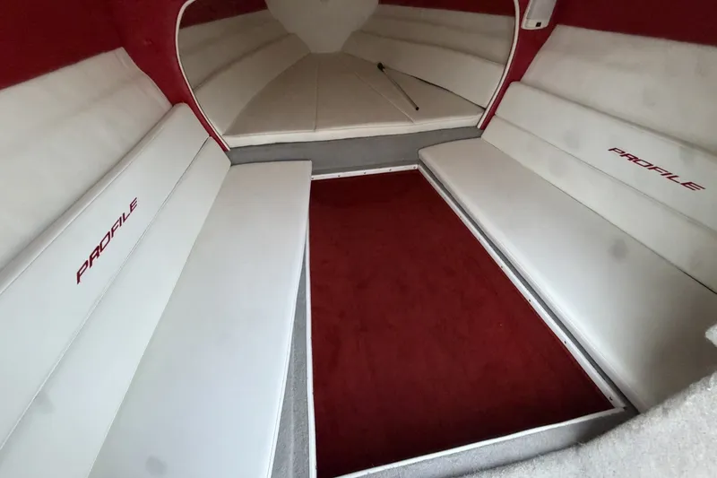 Slide: The Image of Interior of a 2006 Profile 260 V boat with white seating and red accents. - 18