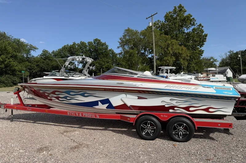 Slide: The Image of 2006 Profile 260 V boat with custom graphics on a red trailer, parked outdoors. - 5