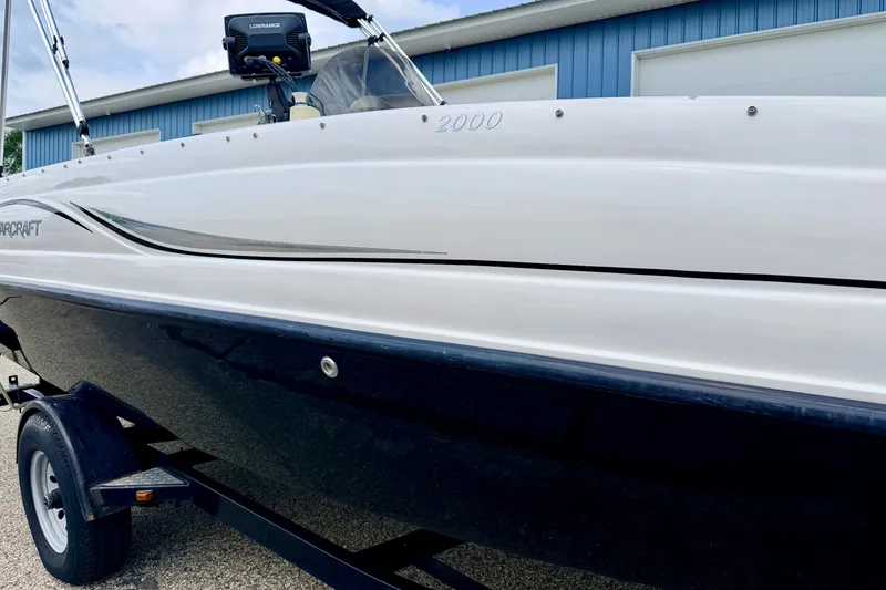 Slide: The Image of 2008 Starcraft 2000 IO Limited boat on trailer, parked near blue building. - 14