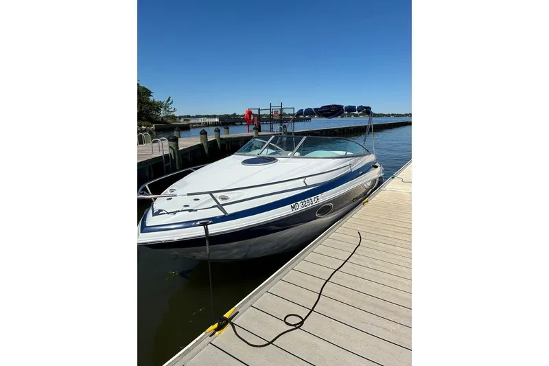 Slide: The Image of 2012 Crownline 236 SC boat docked on a sunny day, showcasing sleek design and blue accents. - 55
