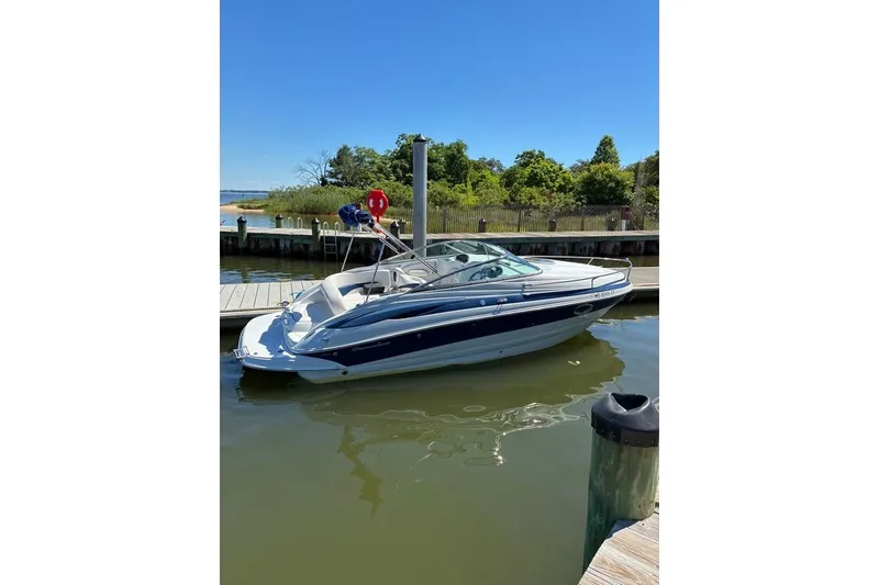 Slide: The Image of 2012 Crownline 236 SC boat docked on a sunny day, surrounded by greenery. - 56