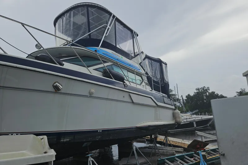 Slide: The Image of 1988 Wellcraft San Remo yacht on dry dock, featuring a covered upper deck. - 36