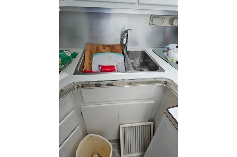 Slide: The Image of 1988 Wellcraft San Remo kitchen area with sink, dishes, and countertop items. - 19