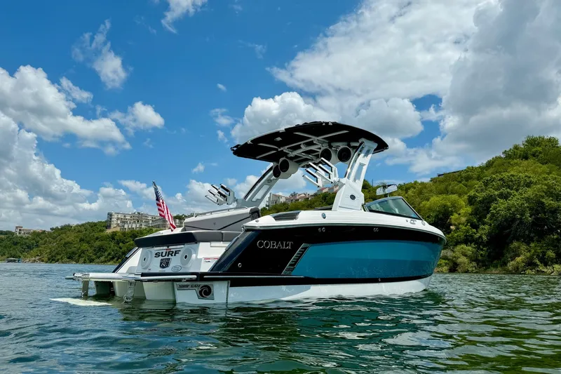 Slide: The Image of 2023 Cobalt R6 Surf boat on a scenic lake under a blue sky. - 7