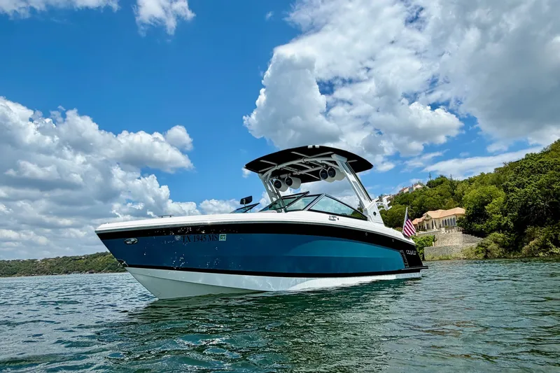 Slide: The Image of 2023 Cobalt R6 Surf boat on a scenic lake under a blue sky. - 3