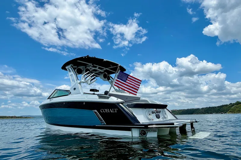 Slide: The Image of 2023 Cobalt R6 Surf boat on water under blue sky with clouds. - 2