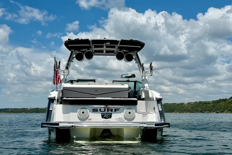Slide: The Image of 2023 Cobalt R6 Surf boat on water, rear view with American flag, under blue sky. - 4