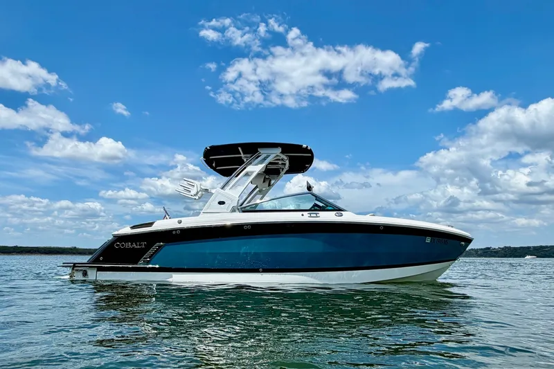 Slide: The Image of 2023 Cobalt R6 Surf boat on calm water under a clear blue sky. - 6