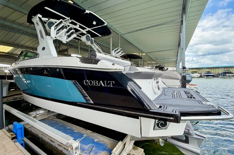 Slide: The Image of 2023 Cobalt R6 Surf boat docked under a covered marina, showcasing sleek design and modern features. - 27