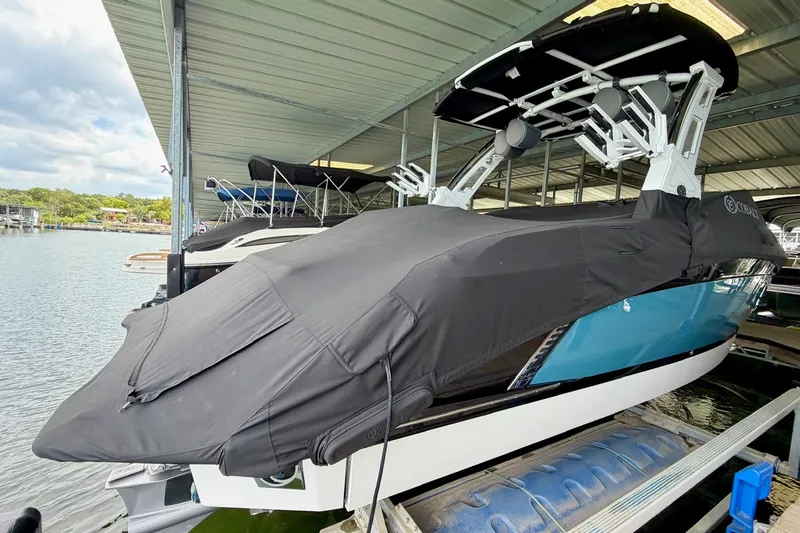 Slide: The Image of 2023 Cobalt R6 Surf boat covered in black tarp, docked under a shelter. - 43