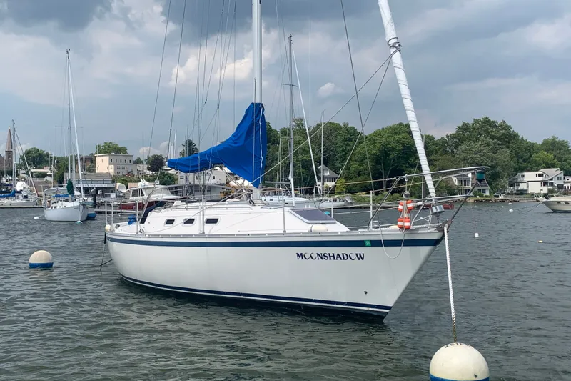 The Image of 1984 CS Sailcraft yacht "Moonshadow" moored in a scenic harbor with cloudy skies. - 0