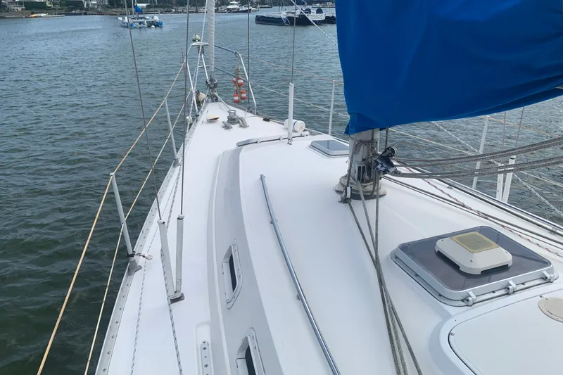 Slide: The Image of 1984 CS Sailcraft sailboat deck with blue sail cover on calm water. - 1