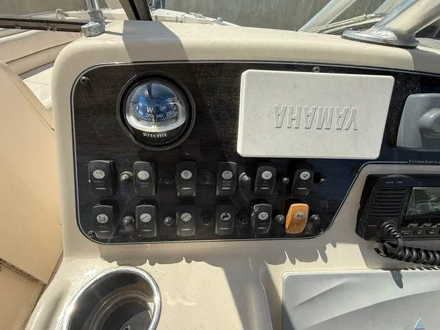 Slide: The Image of The image shows the dashboard of a 2015 Grady-White Freedom 255 boat with various switches and a compass. - 17