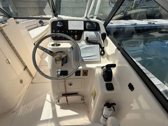 Slide: The Image of The cockpit of a 2015 Grady-White Freedom 255 with a steering wheel, instruments, and a Garmin device. - 7