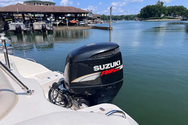 Slide: The Image of 2007 NauticStar 230 Sport Deck with Suzuki outboard motor docked by a scenic marina. - 4