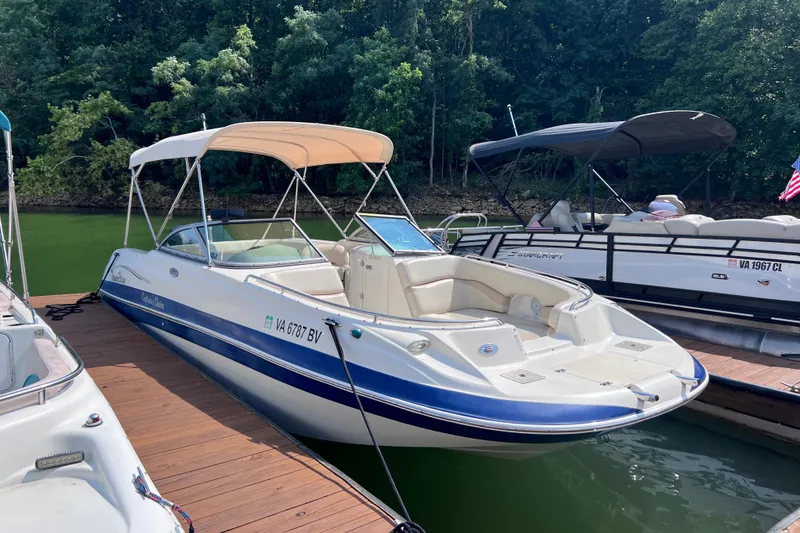 Slide: The Image of 2007 NauticStar 230 Sport Deck boat docked on a sunny day, surrounded by lush greenery. - 3