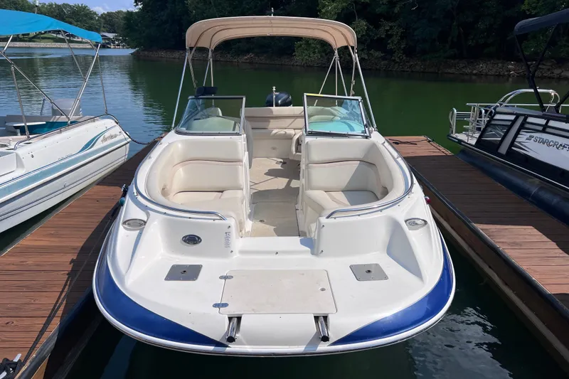 Slide: The Image of 2007 NauticStar 230 Sport Deck boat docked on calm water, featuring spacious seating and canopy. - 1