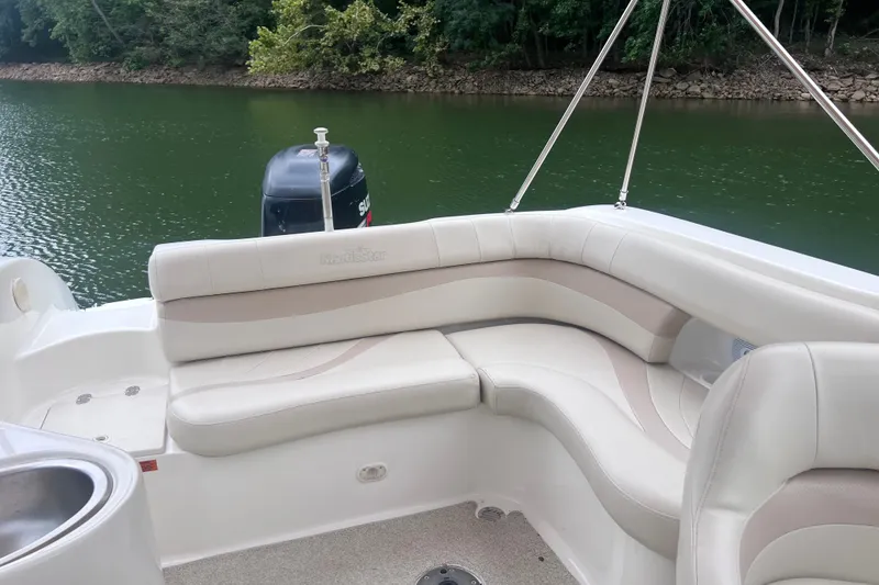 Slide: The Image of 2007 NauticStar 230 Sport Deck boat with white seating, on a calm lake. - 10