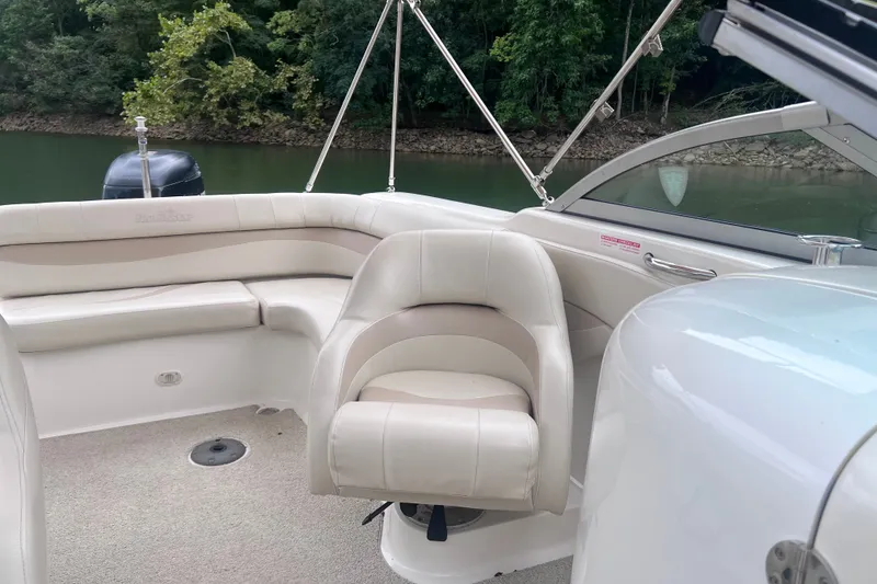 Slide: The Image of 2007 NauticStar 230 Sport Deck boat interior with beige seating, near a forested shoreline. - 8