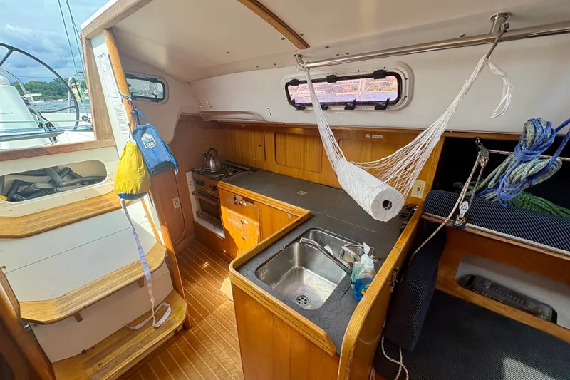 Slide: The Image of Interior of 2000 J Boats J/120 sailboat featuring a compact kitchen and wooden cabinetry. - 16