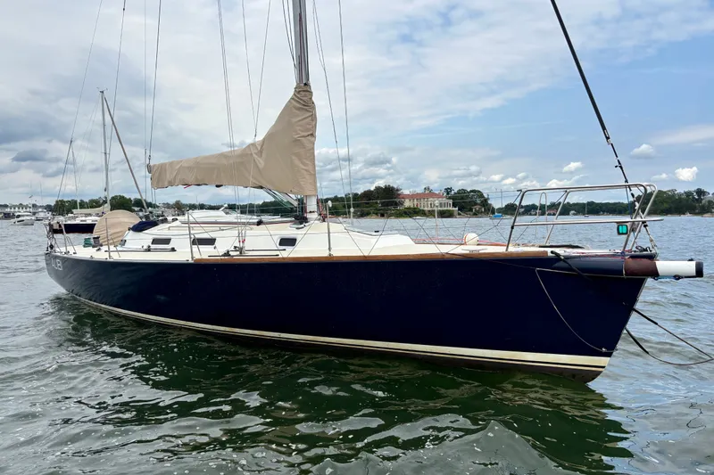 Slide: The Image of 2000 J Boats J/120 sailboat with beige sails on calm water under a cloudy sky. - 1