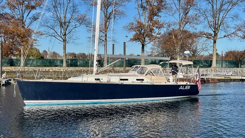Slide: The Image of A 2000 J/120 sailboat with a blue hull, sailing on calm water. - 33