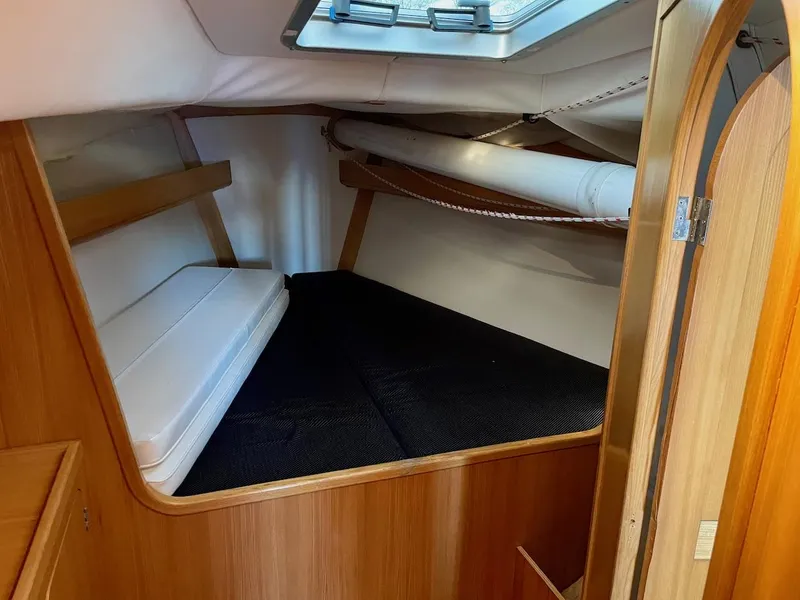 Slide: The Image of The cabin of a 2000 J/120 with a cozy sleeping area and wood paneling. - 24