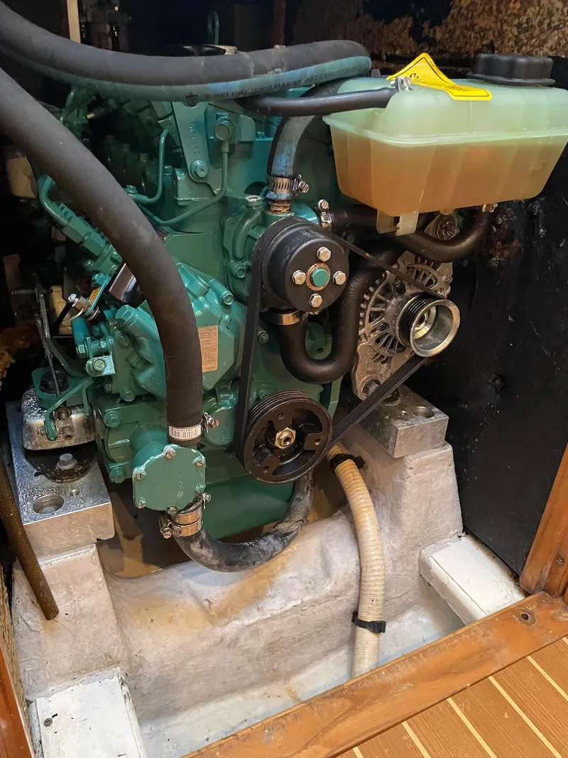 Slide: The Image of A green engine in a boat, surrounded by hoses and a yellow coolant reservoir. - 32