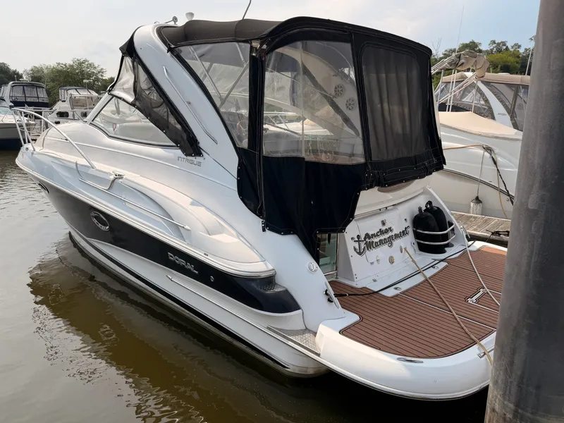 Slide: The Image of A 2005 Doral Intrigue is docked in the water. It features a black canopy and wood platform. - 1