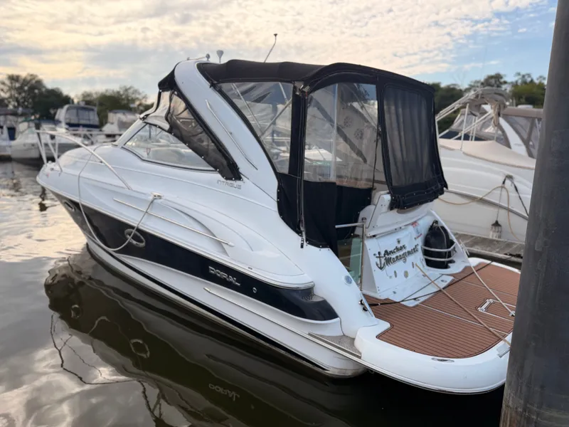The Image of A 2005 Doral Intrigue is docked in the water. It features a black canopy and sleek design. - 2