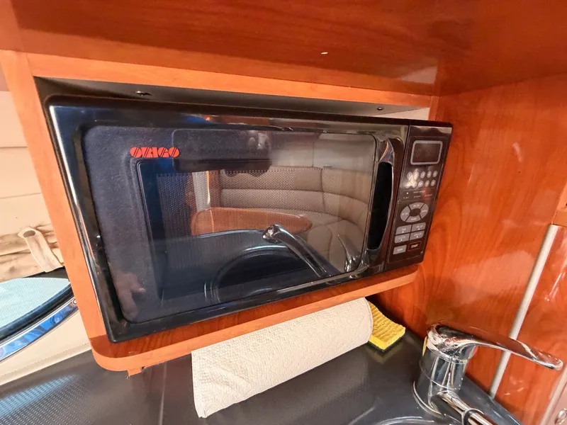 Slide: The Image of A microwave is built into the wooden kitchen of a boat, with a faucet below. - 25