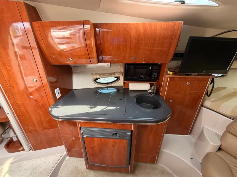 Slide: The Image of The interior of a 2005 Doral Intrigue features a compact kitchen with wood cabinets and a small sink. - 23