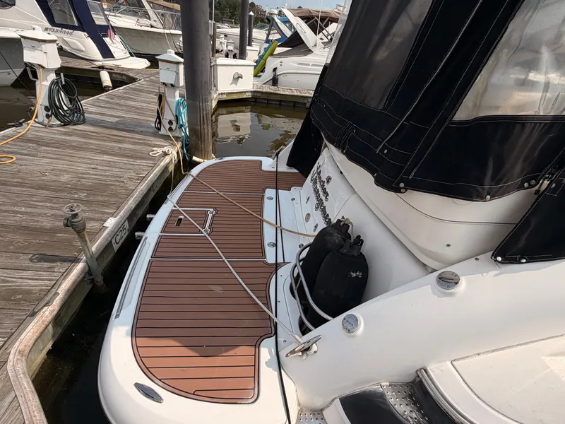 Slide: The Image of A 2005 Doral Intrigue docked at a wooden pier. The boat features a sleek teak deck. - 8