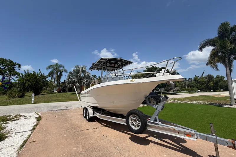 Slide: The Image of 2003 Robalo R230 Center Console boat on trailer, parked outdoors under clear sky. - 4